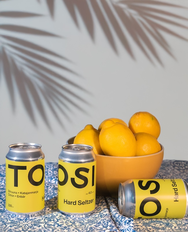 sitruuna-katajanmarja TOSI hard seltzer tölkit ja sitruunoita kulhossa