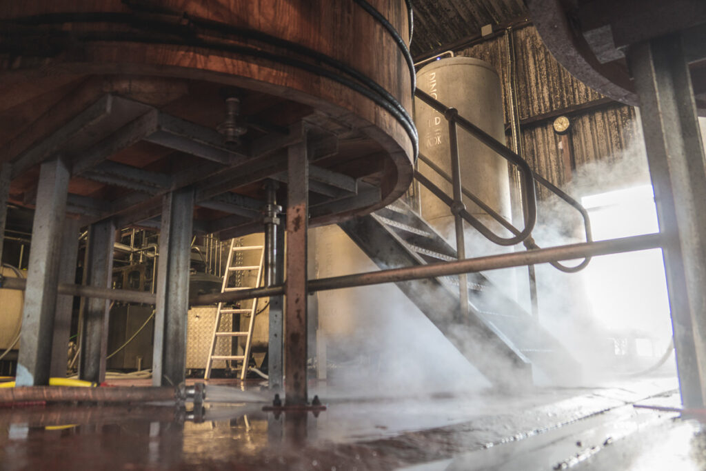 Dingle Distilleryn tuotantolaitteistoa, höyryä, puuta ja metallia maantasosta kuvattuna.