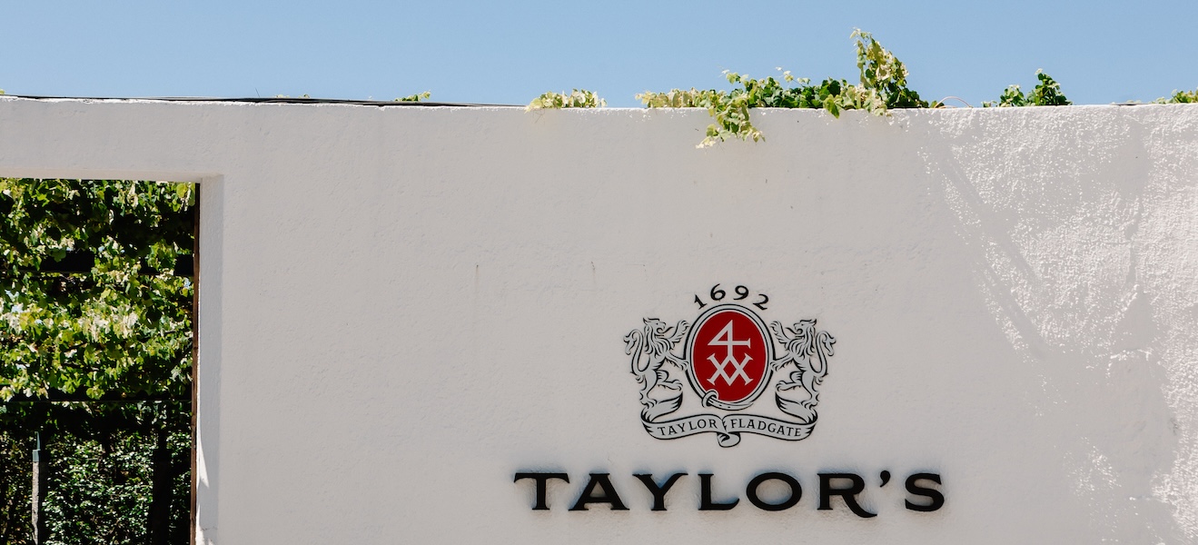 Taylor's vierailukeskuksen sisäänkäynti, valkoinen seinä ja logo