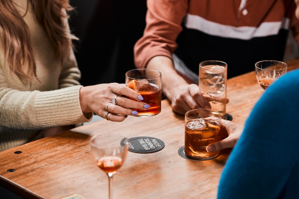 Kolmen ihmisen kädet pitelemässä erilaisia cocktaileja