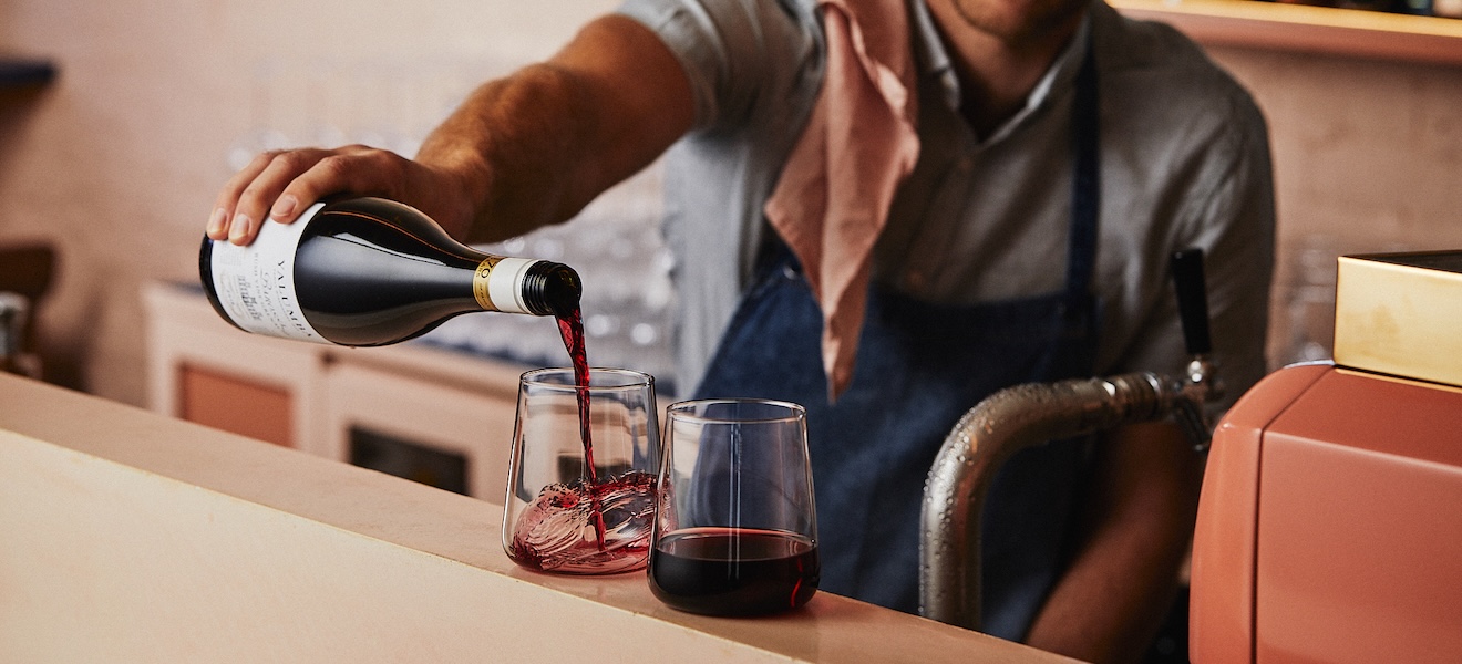 Baarimestari kaataa punaviiniä lasiin